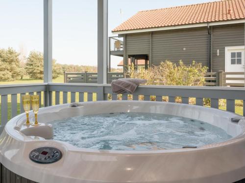 a jacuzzi tub on a deck with a house at Broad Reach - 28121 in Fritton Norfolk