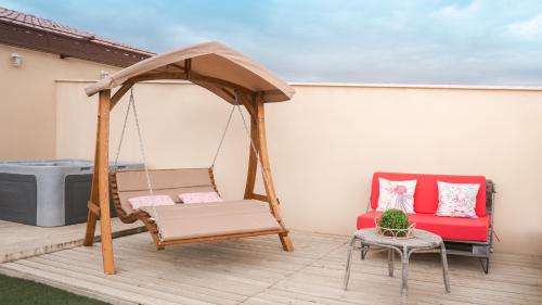 a porch with a swing and a chair and a table at Pâquerette in Arles