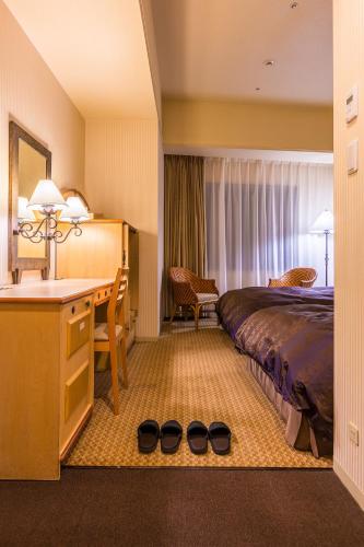 a hotel room with a bed and a desk at Hotel Resol Sapporo Nakajima Koen in Sapporo