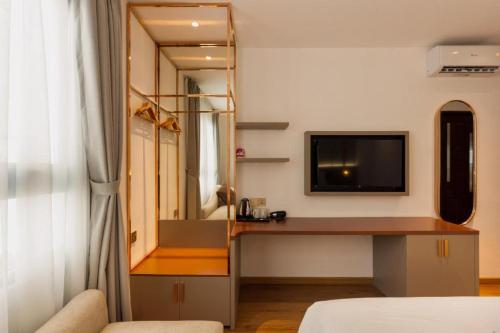 a bedroom with a desk and a tv on a wall at Grand Mays Inn Hotel & Spa in Ho Chi Minh City