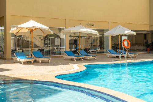 a swimming pool with chairs and umbrellas in a hotel at Seven Seas Jolie Bay - Ultra All Inclusive in Hurghada