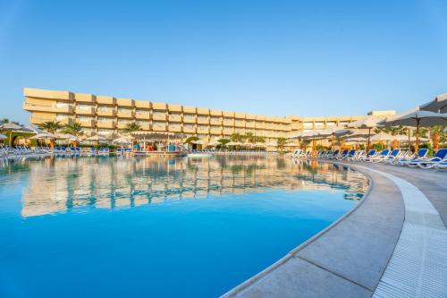 a swimming pool at a resort with chairs and umbrellas at Seven Seas Jolie Bay - Ultra All Inclusive in Hurghada