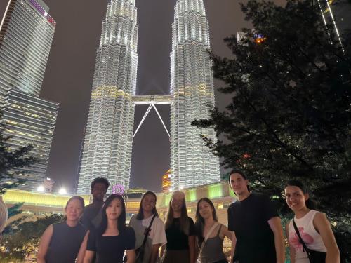 a group of people standing in front of the twin towers at Travelogue Guest House in Kuala Lumpur