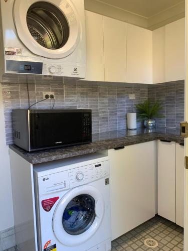 a kitchen with a washing machine and a microwave at Fabulous Stunning Garden View King Bedroom with shared bathroom at MC 2079 in Mount Colah