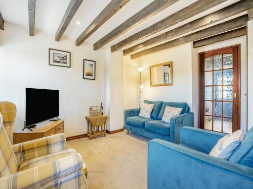ein Wohnzimmer mit blauen Sofas und einem Fernseher in der Unterkunft Black Bull Cottage in Ugthorpe