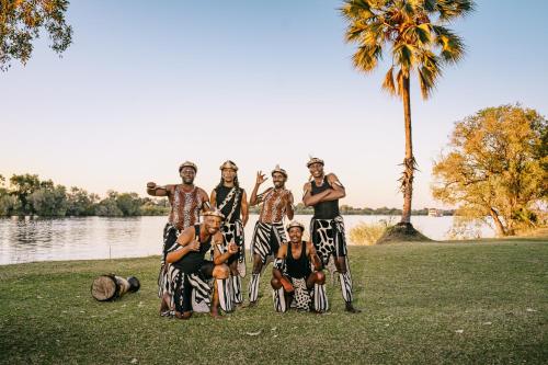 a group of people posing for a picture in front of a lake at Palm River Hotel in Victoria Falls