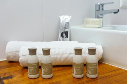 vier flessen vochtinbrengende crèmes op een houten vloer in een badkamer bij Apartamentos Molino by Baiti in Ronda