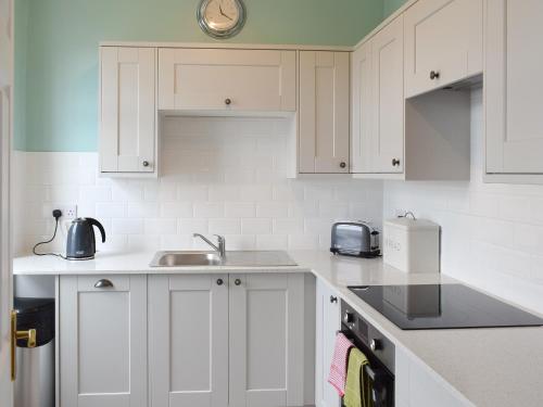 a kitchen with white cabinets and a sink at Mere View in Ambleside