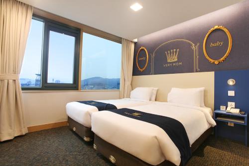 two beds in a hotel room with a sign on the wall at Hotel Skypark Kingstown Dongdaemun in Seoul