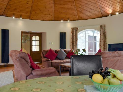 a living room with couches and a table with a bowl of fruit at Horsemill - Uk10794 in Ballingry