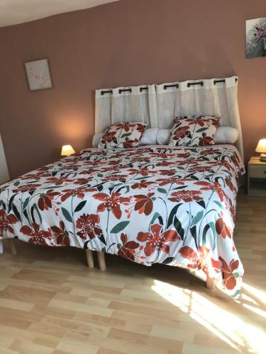 a bedroom with a bed with a floral bedspread at la MAISON de SEVERINE in Abbeville
