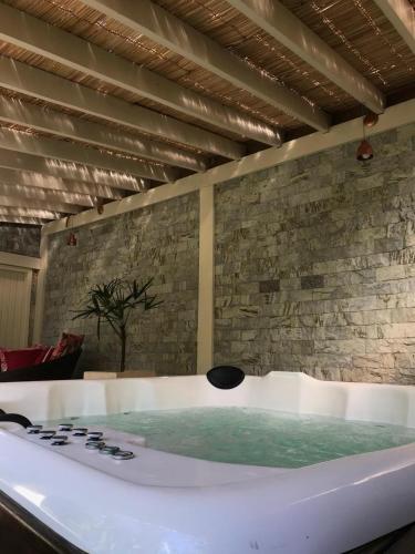 a bath tub in a room with a stone wall at Villa Sana Maritacas in Sana
