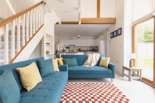 a blue couch in a living room with a staircase at Home Farm Retreat in Cotesbach