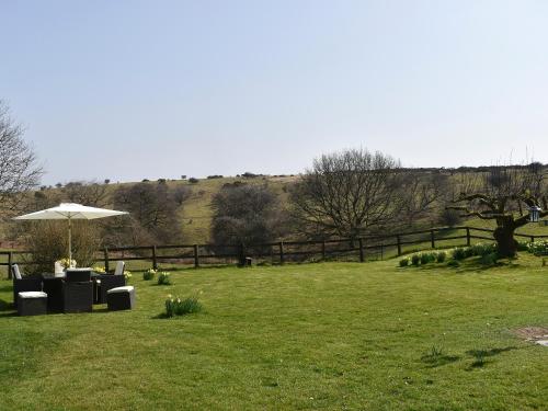 a lawn with an umbrella and chairs in a field at Little Folly in  Liscombe