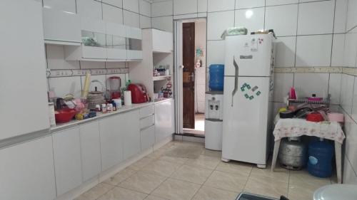 Una cocina con gabinetes blancos y un refrigerador. en Casa para Temporada, en Ananindeua