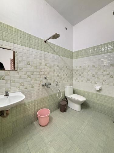 a green tiled bathroom with a toilet and a sink at Maya Residency in Alleppey