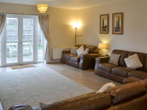 ein Wohnzimmer mit 2 Ledersofas und einem Tisch in der Unterkunft Abbey Cottage in Longhirst