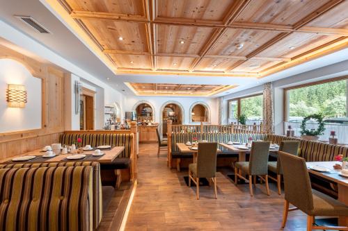 a dining room with wooden tables and chairs at Hotel ALPINJUWEL 3-Sterne Superior in Gerlos