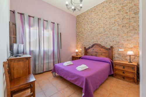 a bedroom with a purple bed and a tv at Hostal el molino in Bezas