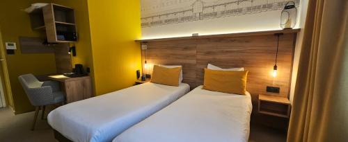 two beds in a hotel room with yellow walls at Hôtel des Halles in Dijon