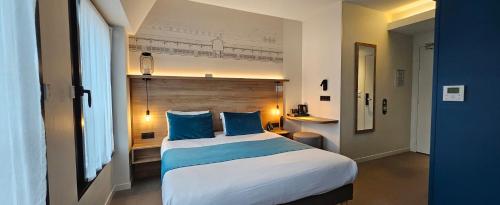 a bedroom with a large bed with blue pillows at Hôtel des Halles in Dijon