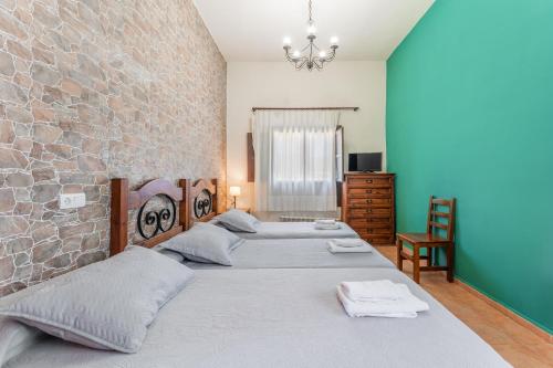 two beds in a room with a stone wall at Hostal el molino in Bezas