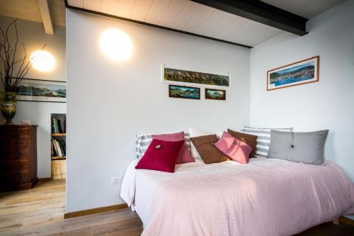a bedroom with a large bed with pink pillows at Loft e Veranda sul Lago di Como in Blevio
