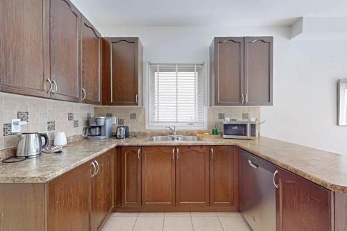 a kitchen with wooden cabinets and a sink at Charming 4-bed Home Away From Home in Brampton, ON in Brampton