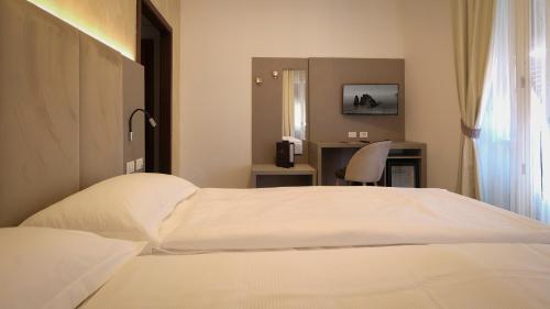 a hotel room with a white bed and a desk at Hotel Margherita in Monterosso al Mare