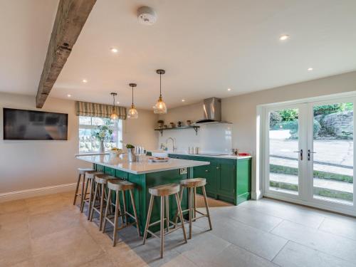 a kitchen with a green island with bar stools at Buryemwick in Timble