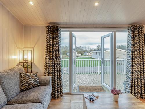 ein Wohnzimmer mit Couch und großem Fenster in der Unterkunft Heather Lodge in Willington