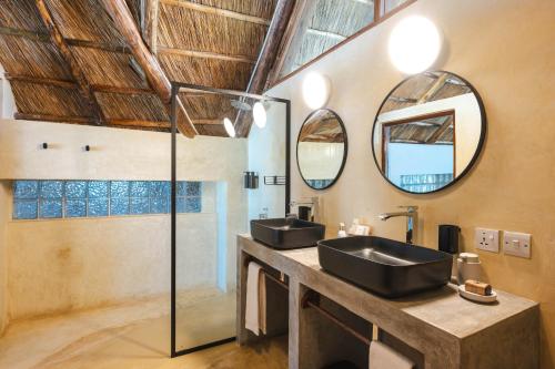 a bathroom with two sinks and a shower at Dar Beach House - Michamvi in Michamvi
