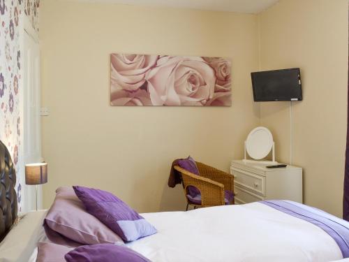 a bedroom with a bed and a painting of a rose at The Gatehouse - Uk2482 in Cayton
