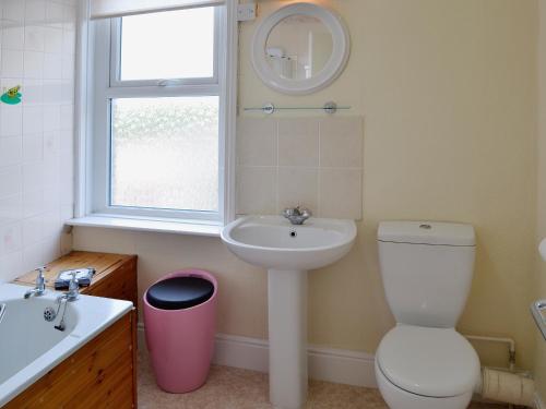 a bathroom with a toilet and a sink and a window at Trevina in Portland