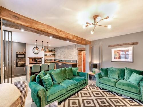 a living room with two green couches and a kitchen at Verona House in Tideswell