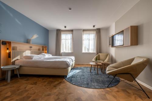 a bedroom with a bed and a chair at Residence Noordstaete - Studio Kluut in Burgh Haamstede