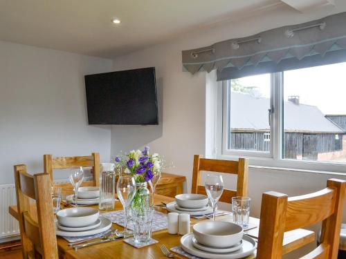 a dining room with a table with chairs and a television at Hillside Cottage in Hanmer