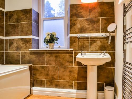 a bathroom with a sink and a tub and a window at Hazelrigg in Bowness-on-Windermere