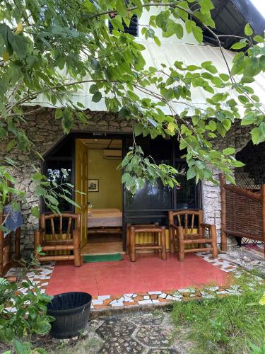 a patio with chairs and a bed in a building at Ravenala Beach Bungalows in Moalboal