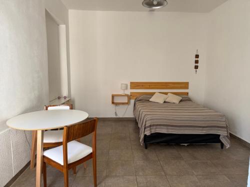 ein kleines Schlafzimmer mit einem Bett, einem Tisch und einem Stuhl in der Unterkunft Departamento Amoblado in Villa María