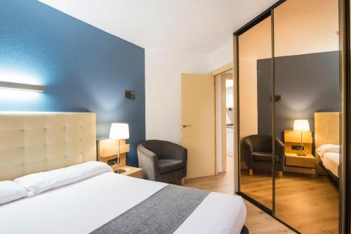 a hotel room with a bed and two chairs at Alda Don Carlos in Santander