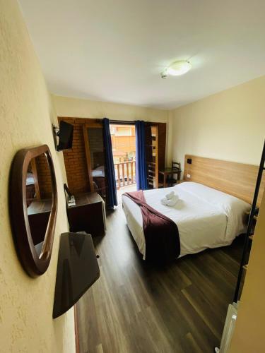 a hotel room with a bed and a balcony at Hotel Garnier in Campos do Jordão