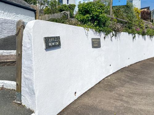 a white wall with two signs on it at Summers Beach View in Saint Mawes