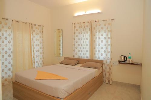 a bedroom with a bed with white sheets and curtains at PRS CREEK SIDE HOME STAY VILLA in Yelagiri