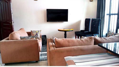 a living room with two couches and a flat screen tv at TOQUe HOTEL & ACCOMODATIONS in Gatunga