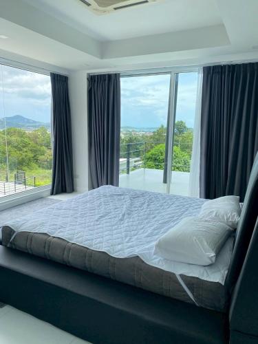 een slaapkamer met een bed en een groot raam bij modern hillside home in Ban Ko Khwan