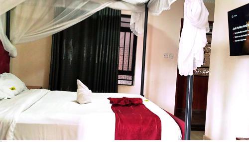 a bedroom with a bed with a red dress on it at TOQUe HOTEL & ACCOMODATIONS in Gatunga
