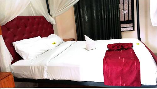 a bedroom with a white bed with a red headboard at TOQUe HOTEL & ACCOMODATIONS in Gatunga