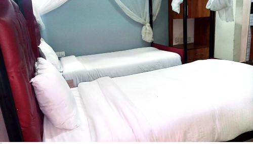 two beds in a small room with white sheets at TOQUe HOTEL & ACCOMODATIONS in Gatunga
