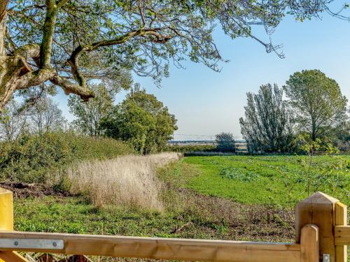 a wooden fence next to a field with a tree at Mark Farmhouse in Bradwell on Sea